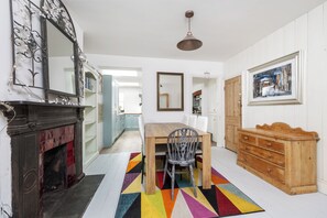 A dining area with a wooden table, chairs, a colorful rug, a fireplace, and a mirror on the wall. - Period Home in the Heart of Winchester (Winchester)