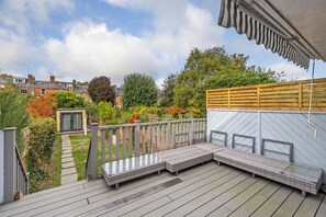 A deck with a built-in seating area, a wooden fence, and a garden with various plants and a pathway. - Period Home in the Heart of Winchester (Winchester)