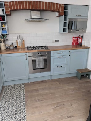 A kitchen with a gas stove, oven, and a small wooden stool. - Period Home in the Heart of Winchester (Winchester)