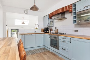 Una cocina moderna con armarios azul claro, encimera de madera, estufa a gas y horno empotrado.