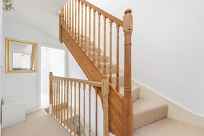 A wooden staircase with a handrail, carpeted steps, and a white wall with a framed picture. - Period Home in the Heart of Winchester (Winchester)
