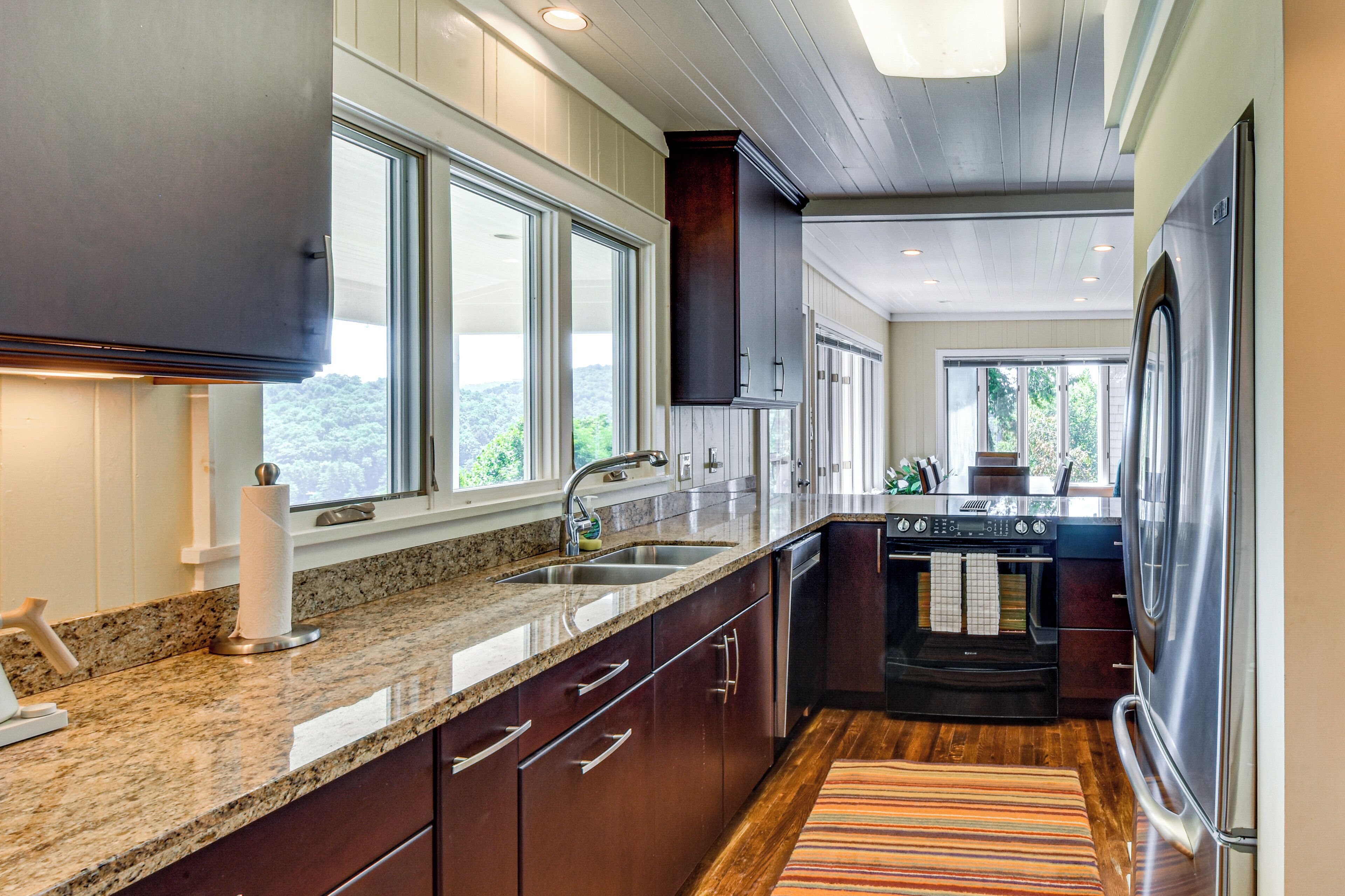 A modern kitchen with granite countertops, stainless steel appliances, and large windows.