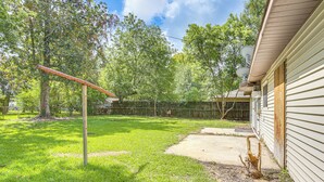 A backyard with a swing set, a wooden fence, and a house with satellite dishes. - 4 Mi to Sabine River! Extended Escape w/ Yard (Orange)