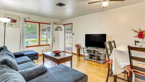 A living room with a sofa, a coffee table, a TV, and a dining area with chairs and a table. - 4 Mi to Sabine River! Extended Escape w/ Yard (Orange)