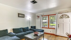 A living room with a wooden floor, two dark sofas, a coffee table, and a window with curtains. - 4 Mi to Sabine River! Extended Escape w/ Yard (Orange)