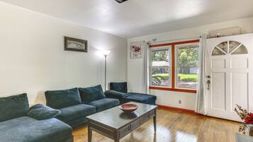 A living room with a wooden floor, two dark sofas, a coffee table, and a window with curtains.