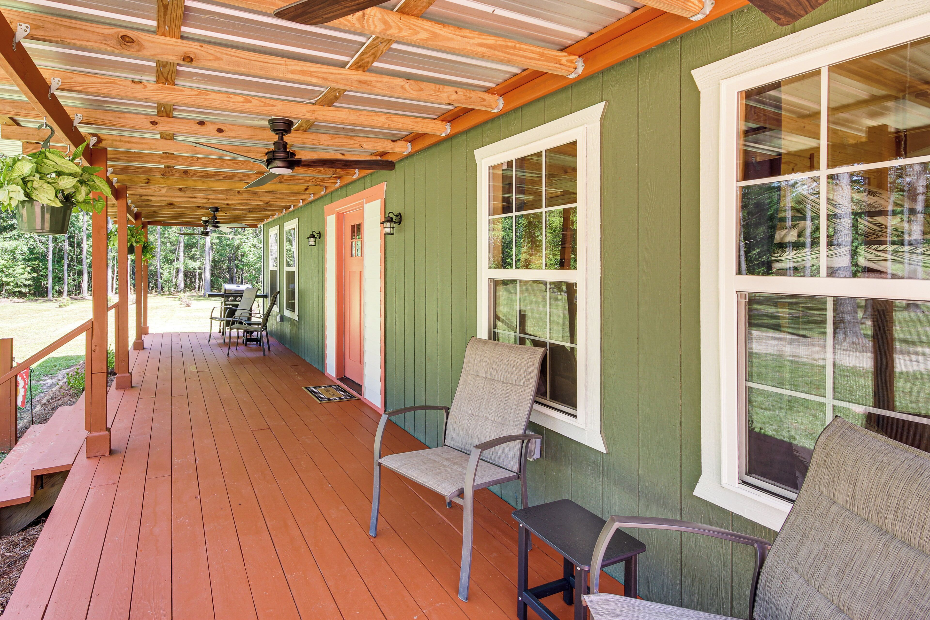 A covered porch with wooden beams, a table with chairs, and a view of the outdoors.