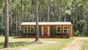 A small cabin with a porch, surrounded by a forest.