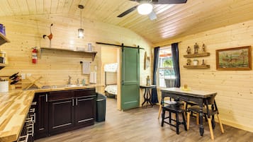 A wooden interior with a kitchen, dining area, and a door leading to another room.