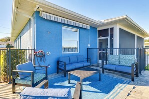 Ein blaues Gebäude mit einer Terrasse, ausgestattet mit einer Couch, Stühlen und einem Tisch.