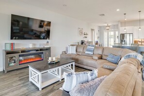 Ein modernes Wohnzimmer mit großem Flachbildfernseher, einer Eckcouch, einem Couchtisch und einem Kamin.