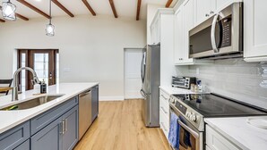 A modern kitchen with a stainless steel refrigerator, built-in microwave, and a black induction cooktop. - Boat Dock & Poolside Fun! Twin Houses on Lake Clay (Lake Placid)