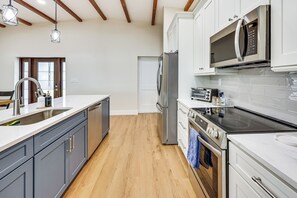Eine moderne Küche mit einem Edelstahl-Kühlschrank, einer eingebauten Mikrowelle und einer schwarzen Induktionskochplatte.