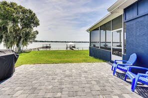 Eine Terrasse mit Seeblick, ein überdachter Bereich mit Tisch und Stühlen sowie ein Grill.