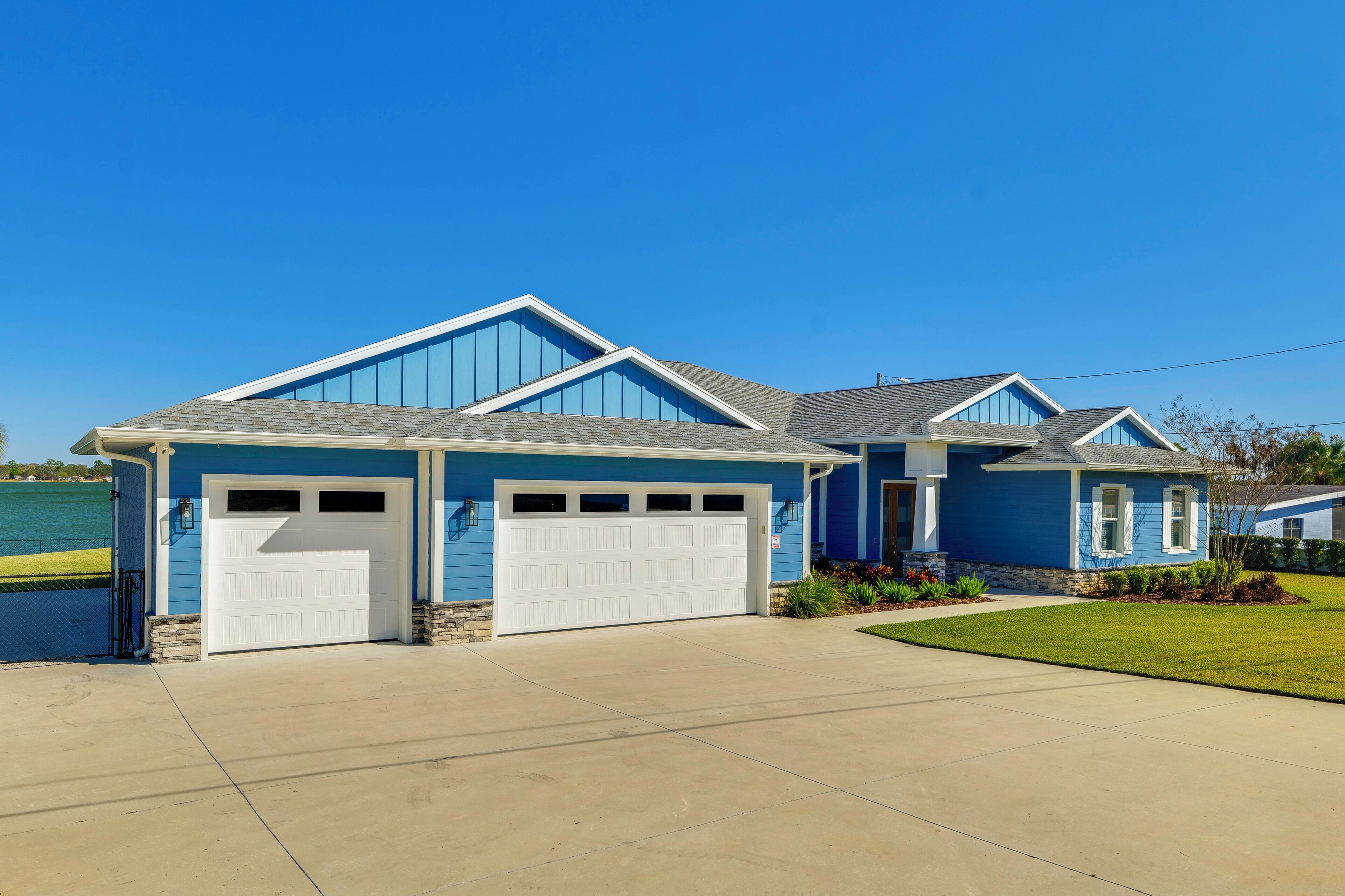 A two-story house with a blue exterior and white garage doors.