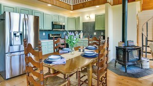 A modern kitchen with wooden cabinets, stainless steel appliances, and a dining area with a wooden table set for four. - Fisherman's Retreat on Lake Ontario, Near Marina (Cape Vincent)