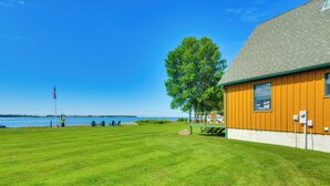 A grassy area with a building, a flag, and a tree. - Fisherman's Retreat on Lake Ontario, Near Marina (Cape Vincent)