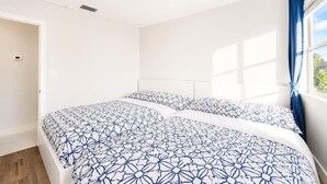 A bedroom with a bed, a window with curtains, and a ceiling light.