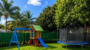 A playground with a swing set, slide, and trampoline.
