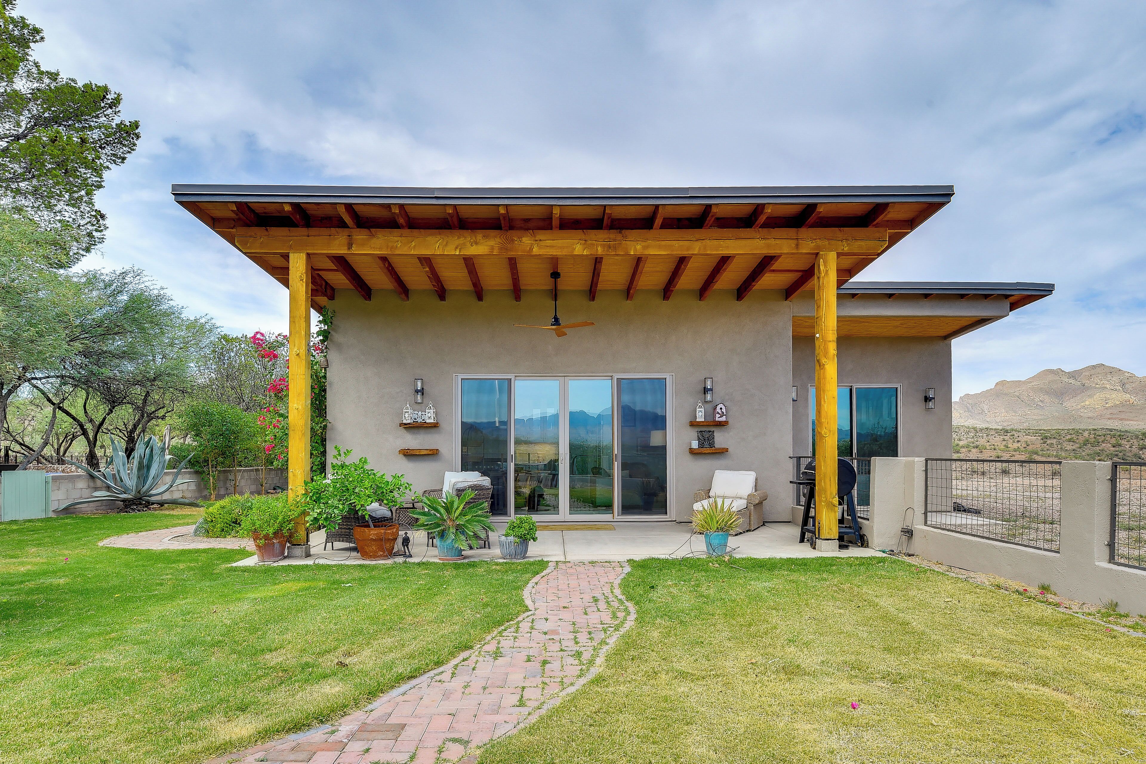 A modern house with a covered patio, large sliding glass doors, and a landscaped yard.
