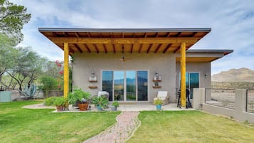 A modern house with a covered patio, large sliding glass doors, and a landscaped yard.