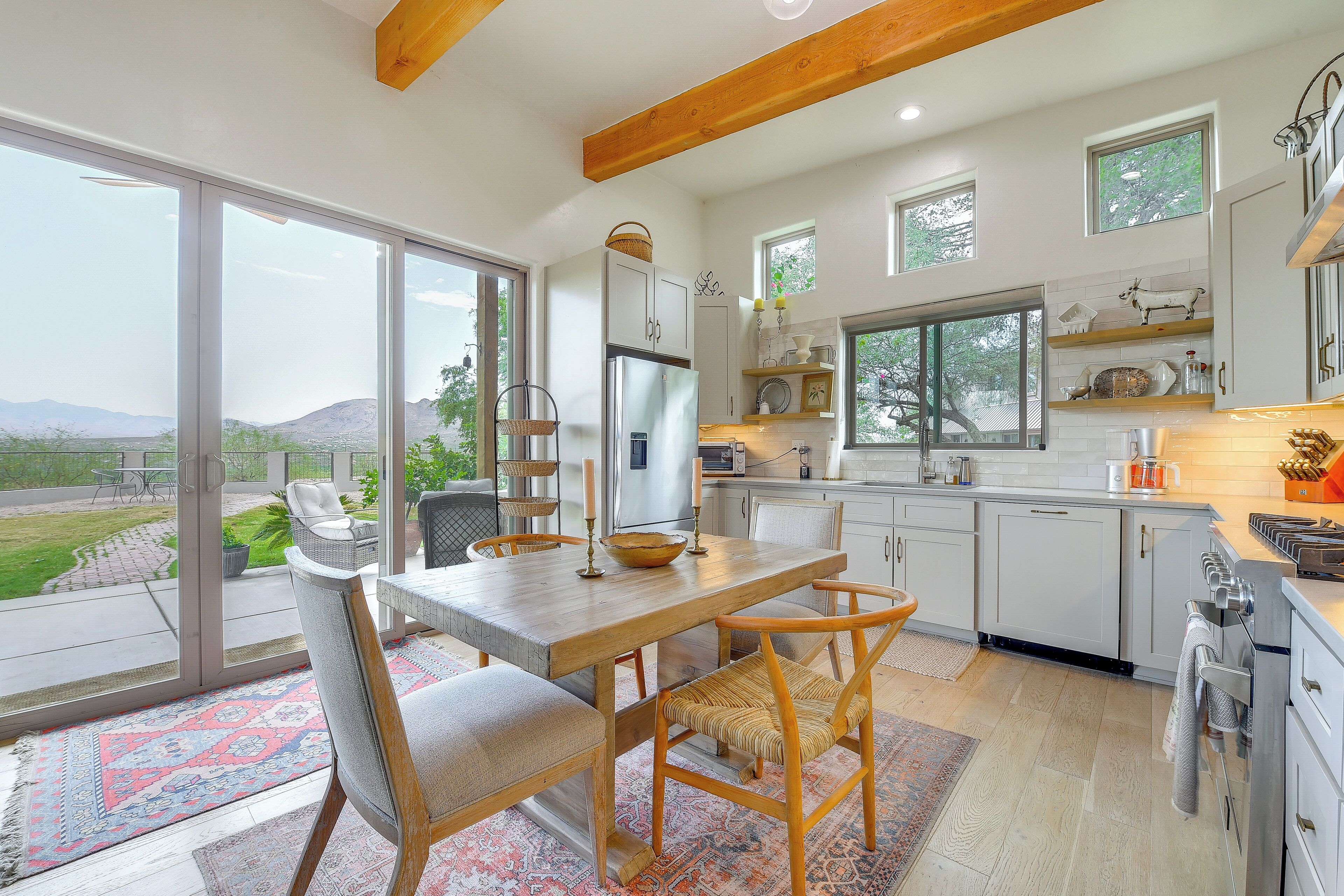 A modern kitchen with a large island, white cabinetry, and a view of the outdoors.