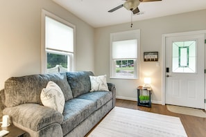 A living room with a gray sofa, a white rug, and a door with a green glass window.