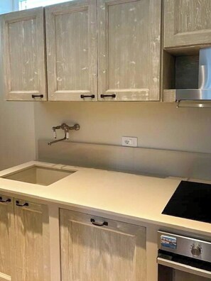 Eine Küche mit Holzausstattung, einer Edelstahl-Dunstabzugshaube, einem Spülbecken und einem eingebauten Backofen.