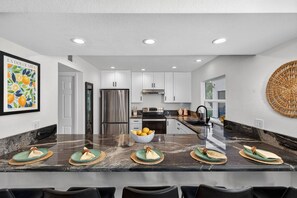 A modern kitchen with white cabinets, stainless steel appliances, and a marble countertop. - Mesa Retreat Heated Pool Game Room Great For Families (Mesa)