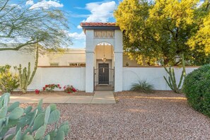 A house with a white exterior, a red-tiled roof, a black gate, and a cactus garden. - Walk to Spring Training Heated Pool Sleeps 12 (Mesa)