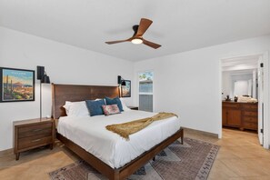 A bedroom with a bed, a nightstand, a dresser, a ceiling fan, a framed picture, and a window. - Walk to Spring Training Heated Pool Sleeps 12 (Mesa)