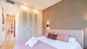 Quarto de hotel com cama, guarda-roupa, luz acoplada à parede e corredor.