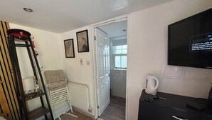 Een slaapkamer met een bed, een radiator, een stoel, een televisie en een waterkoker.