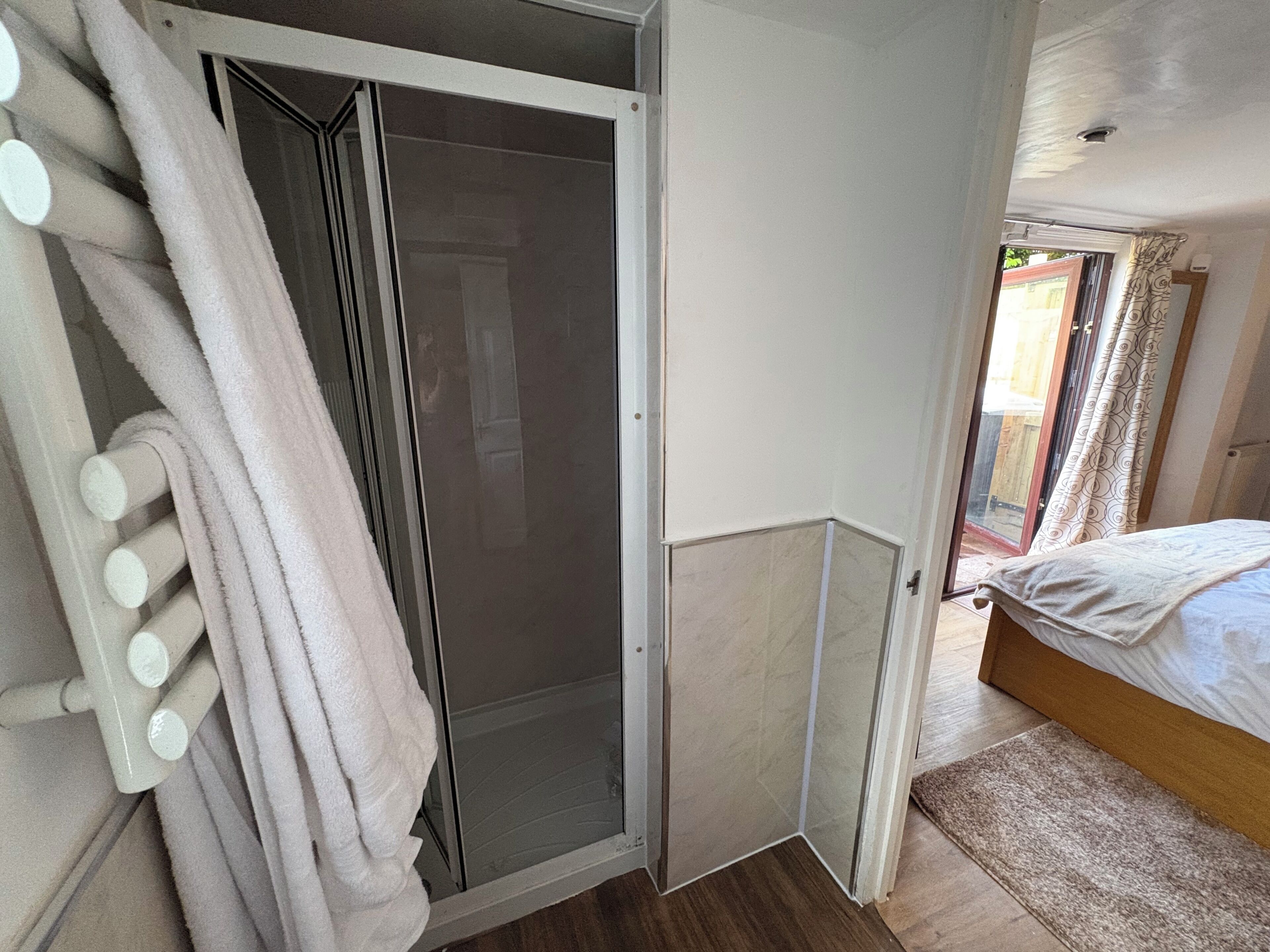 Ein Schlafzimmer mit einem Bett, einer Dusche und einem Badezimmer mit Handtuchhalter.