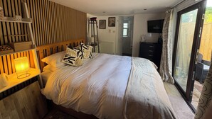 Een slaapkamer met een bed, nachtkastjes, een lamp, een televisie en een schuifdeur naar buiten.