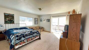 Une chambre à coucher comprenant un lit, un canapé, une armoire en bois et une fenêtre avec des stores.
