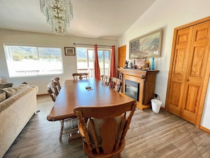 A dining area with a wooden table, chairs, a fireplace, and a large window with a view. - Family Ranch house with Mountain View’s (Crestone)