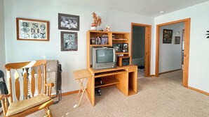 A room with a wooden entertainment center, a television, a chair, and framed pictures on the wall. - Family Ranch house with Mountain View’s (Crestone)