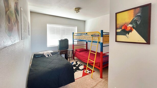 A bedroom with bunk beds, a television, a desk, and a window with blinds. - Family Ranch house with Mountain View’s (Crestone)