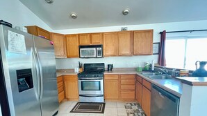 A kitchen with wooden cabinets, stainless steel appliances, a microwave, a stove, and a sink. - Family Ranch house with Mountain View’s (Crestone)