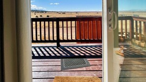 A view from a room with a door leading to an outdoor deck with a wooden railing and a clear blue sky. - Family Ranch house with Mountain View’s (Crestone)