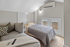 Une chambre à coucher avec un lit, un canapé, une table de chevet, une lampe et une fenêtre.