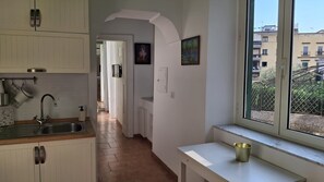 A kitchen with a sink, cabinets, and a window overlooking a residential area. - 38 Stay (Naples)