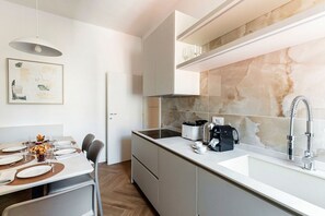 A modern kitchen with a white countertop, stainless steel appliances, and a marble backsplash. - The Monti Residence - My Home in Como (Como)