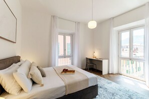 A bedroom with a bed, a desk, and large windows. - The Monti Residence - My Home in Como (Como)