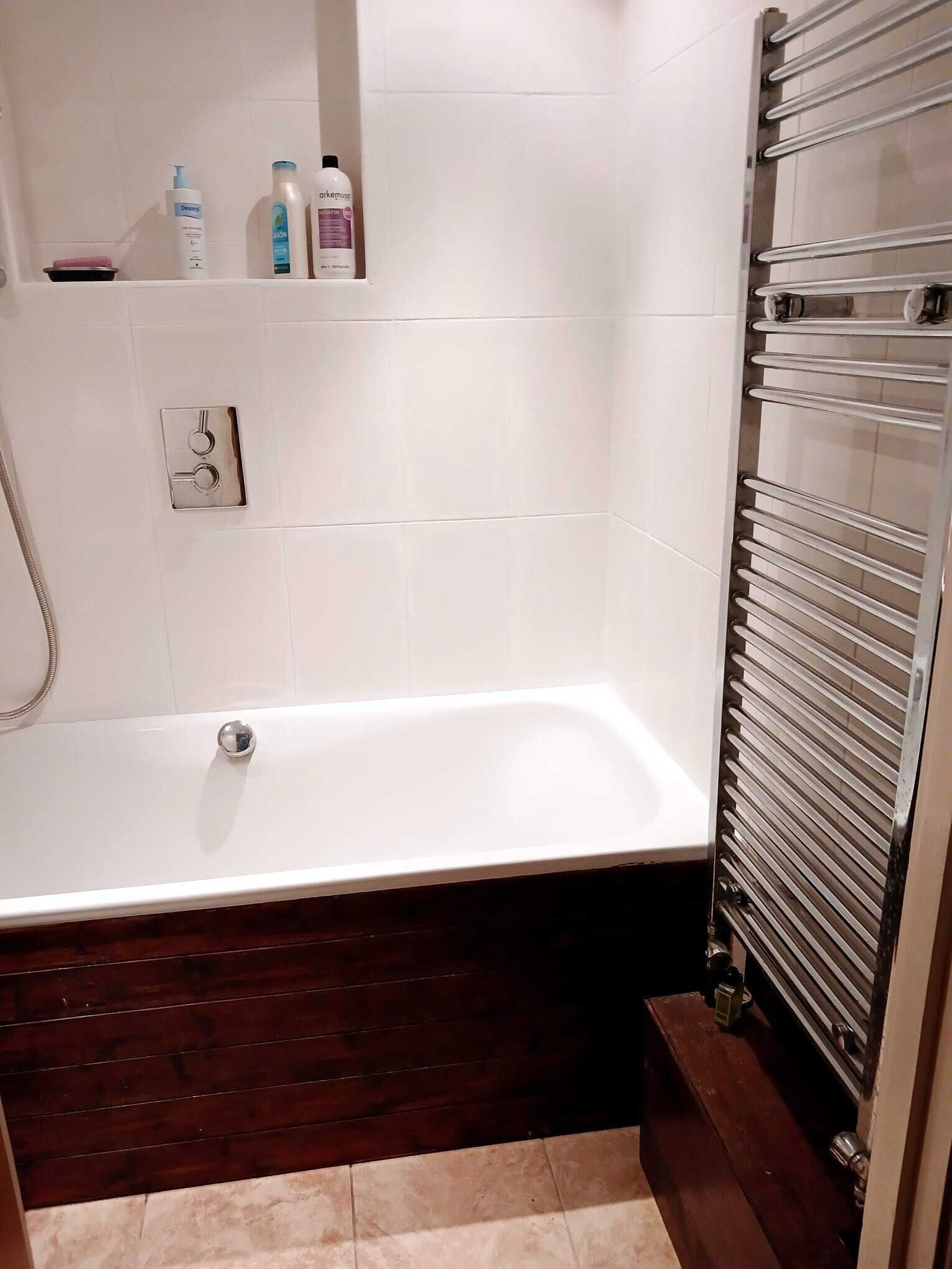 Ein Badezimmer mit einer weißen Badewanne, einer Dusche und einem Handtuchhalter.