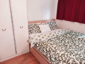 A bedroom with a bed, a wardrobe, and a red curtain. - Cosy Apartment London (London)