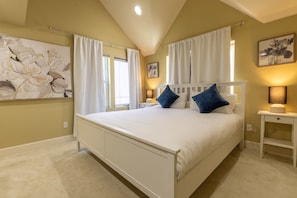 A bedroom with a large bed, white curtains, a bedside table with a lamp, and a wall-mounted painting. - Oceana: Peaceful 5-bedroom Seattle Home 10 mins to DT (Seattle)