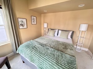 Ein Schlafzimmer mit einem Bett, zwei Wandleuchten und zwei gerahmten floralen Kunstwerken.