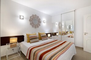 Une chambre d’hôtel comprenant un lit, des tables de chevet, un miroir et un luminaire fixé au mur.